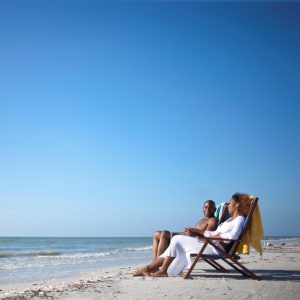A man and a woman sit on a chair in front of a lake